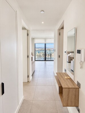 Habitació d'hotel moderna amb un balcó, una banca de fusta i un mirall gran.