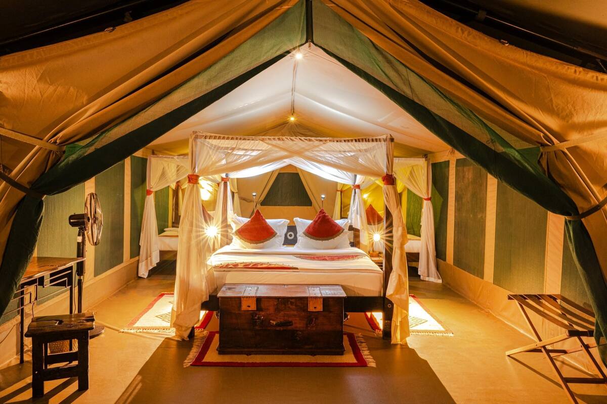 Ein Zeltraum mit einem Bett, einer Holzkiste und einem Ventilator.
