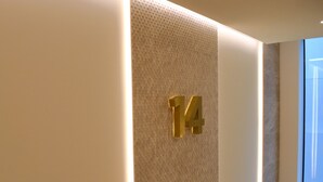 Een muur met een structuur en een groot, gouden cijfer '14'.