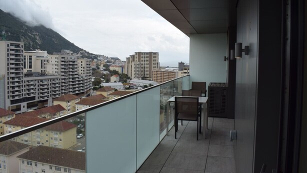 Een balkon met uitzicht op een stadsbeeld en bergen.