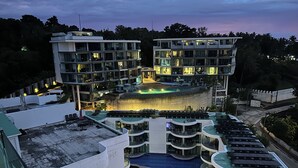 Ein modernes Hotel mit mehreren Balkonen, einem Schwimmbad und einer Dachterrasse.