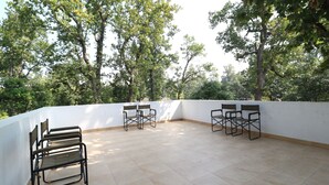 An outdoor terrace with tiled flooring and metal chairs.