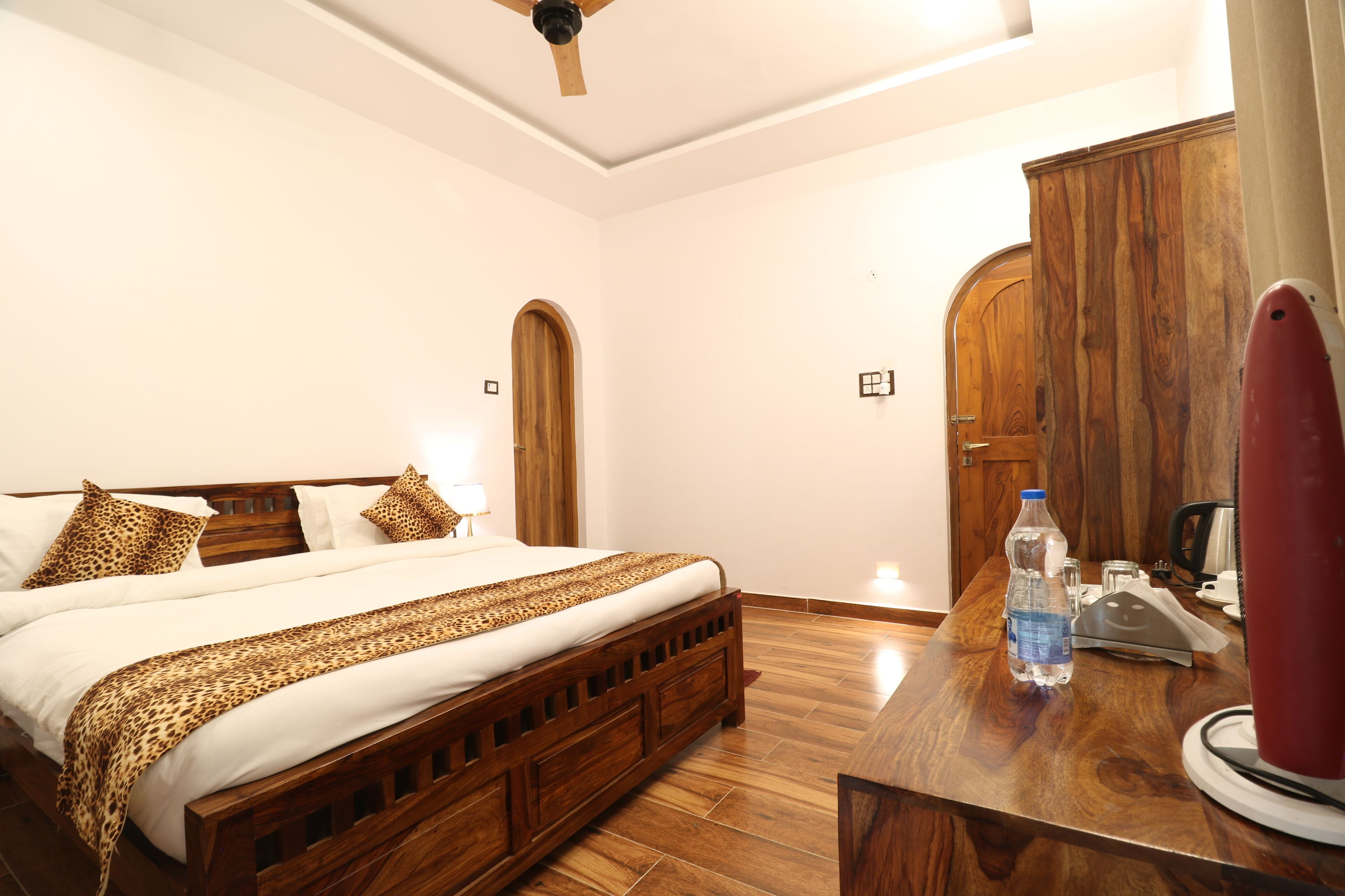 A hotel room with a wooden bed, a wooden desk, and a wardrobe.
