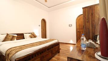A hotel room with a wooden bed, a wooden desk, and a wardrobe.