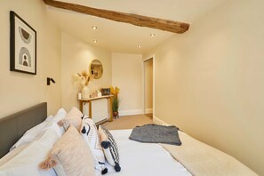 Een slaapkamer met een bed, nachtkastje en spiegel.