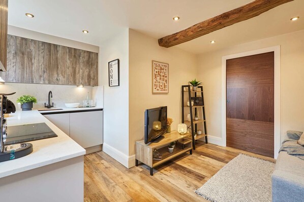 Een moderne keuken met een houten accentmuur, een inbouwspoelbak en een eethoek met een houten tafel en stoelen.