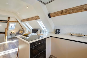 Una cocina moderna con una isla central, horno empotrado y tragaluces.