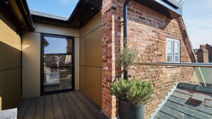 Eine Dachterrasse mit Holzdeck, einem Blumentopf und einer Ziegelwand.