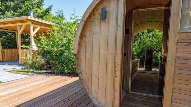 A wooden structure with a curved entrance and a wooden deck. - Lieblingshof House 4 - Holidays between the Baltic Sea and the Bodden (Born a. Darß)