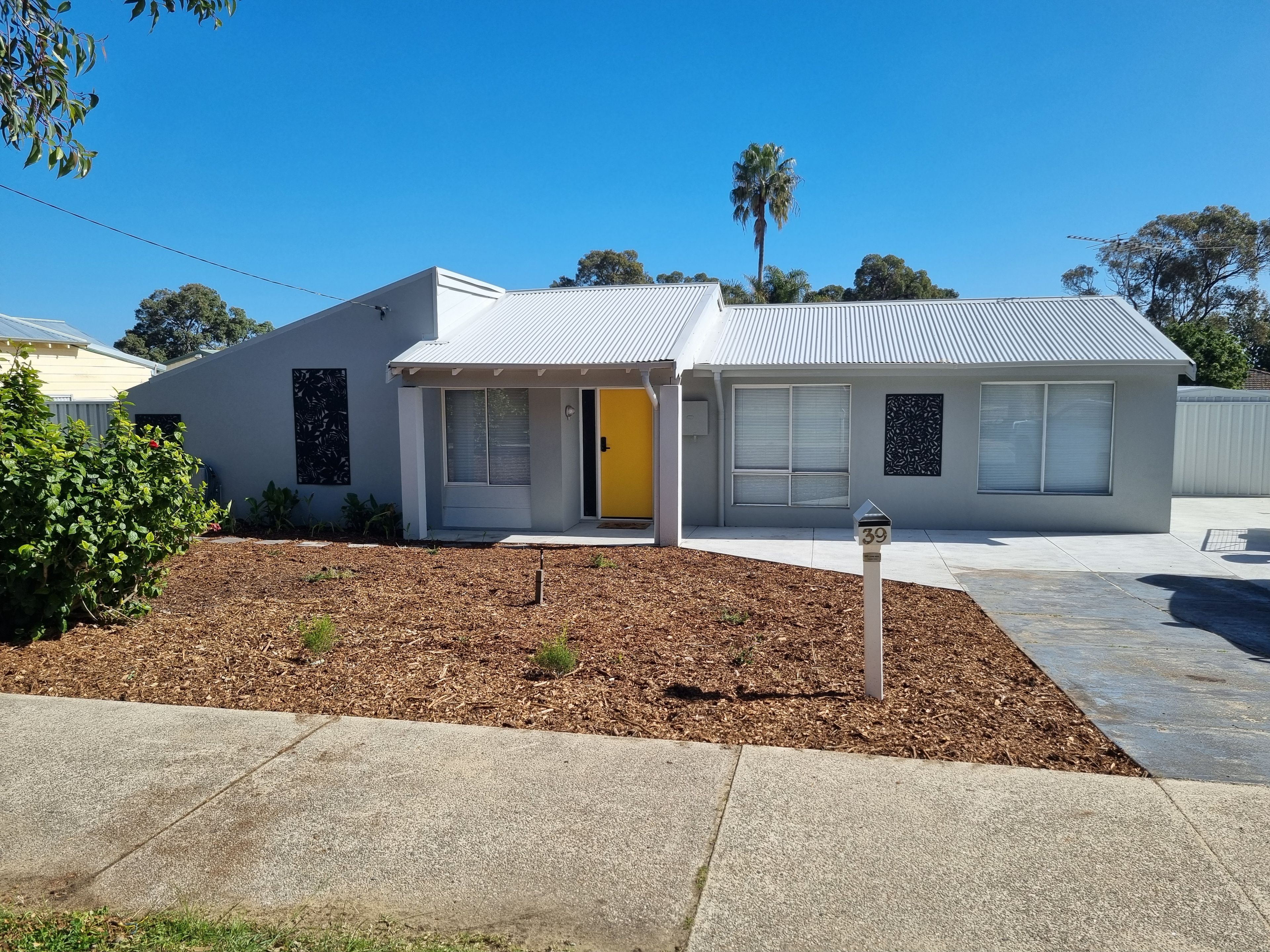 A modern two-story house with a yellow door, a covered porch, and a well-maintained front yard.
