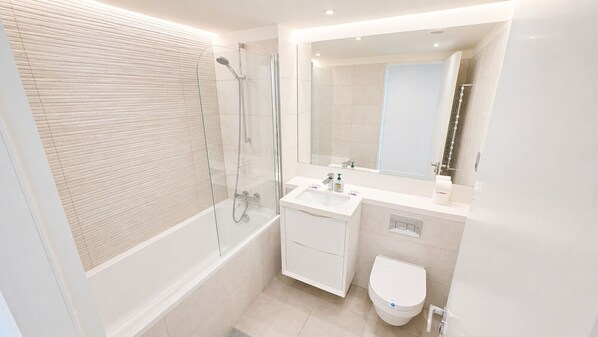 Un baño moderno con ducha envuelta en vidrio, un lavabo blanco y un inodoro.