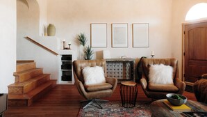 A spacious living room with a wooden staircase, leather armchairs, a small round table, and a fireplace. - Lux Casa HotTub + Sauna w/ Mtn Views, DT 10mins (Santa Fe)