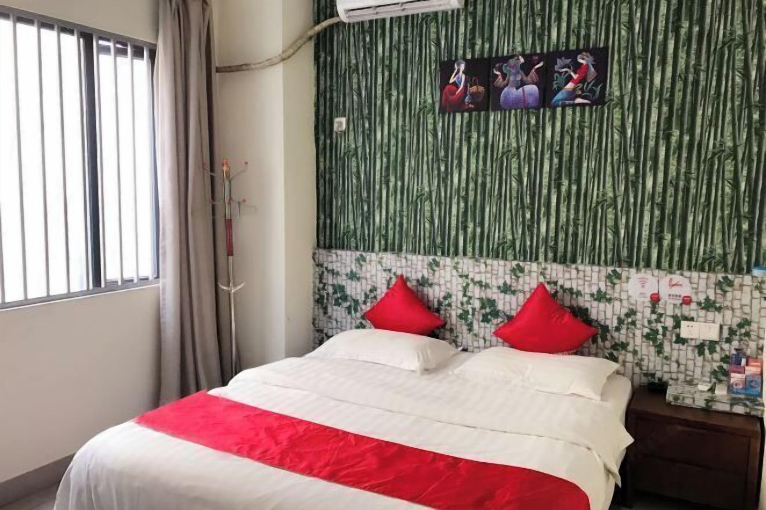 A hotel room with a bed, a window with blinds, a wall with a bamboo pattern, and a wall with a mosaic design.