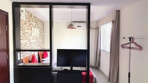A room with a bed, a desk, a chair, a hanging light fixture, and a window with curtains. - Sanya Mingjing Express Hotel (Sanya)