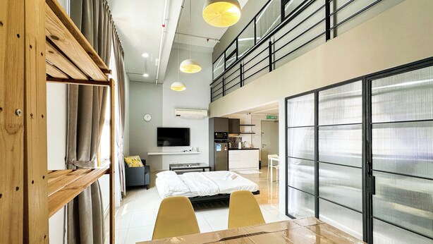 A modern hotel room with a bed, a desk, a TV, and a kitchenette.