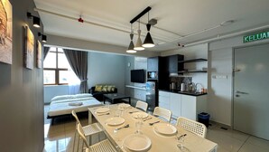A modern hotel room with a dining area, kitchenette, and a bed.