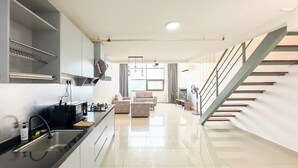 A modern kitchen with a central island, a dining area with a sofa, and a staircase leading to an upper level.