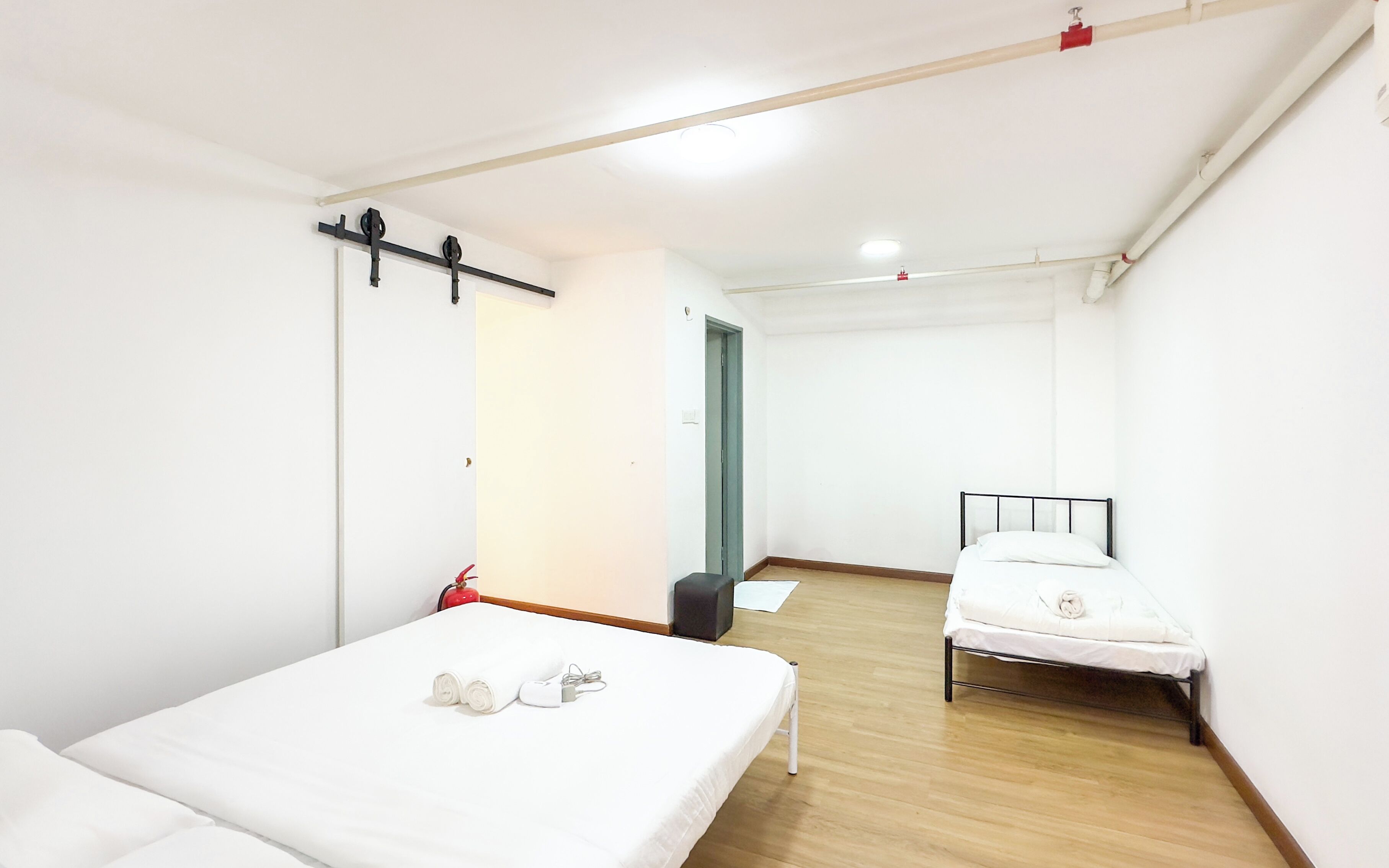 A room with a bed, a desk, and a chair. There is a door leading to another room.