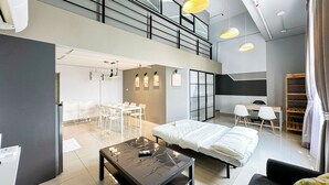 A modern hotel room with a bed, a desk, and a dining area.