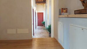 A hallway with wooden flooring, a red door at the end, and a radiator on the right wall. - Il Carro Rooms (Monza)