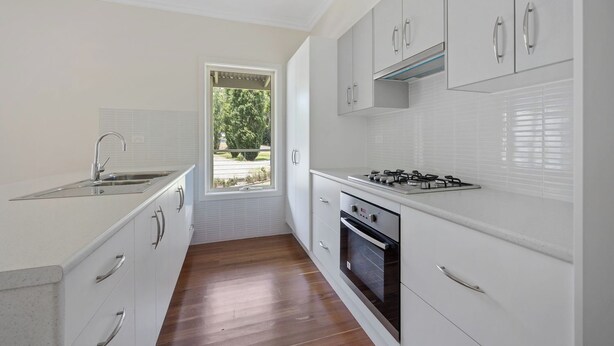 A modern kitchen with white cabinetry, a stainless steel sink, a gas stove, and an oven. - Warm Country Side Home (Buxton)