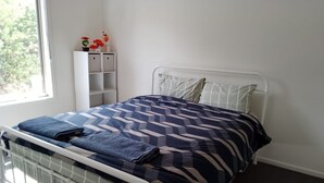 A bed with a metal frame, a patterned bedspread, and pillows. There is a window with a view of trees outside. - Warm Country Side Home (Buxton)