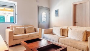 A living room with two beige sofas, a wooden coffee table, and a window with blinds.