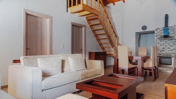 A modern living room with a sofa, coffee table, and a wooden staircase.