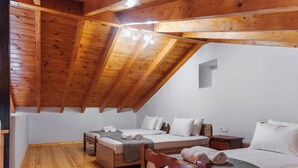 A cozy attic bedroom with wooden beams, two beds, and a small seating area.