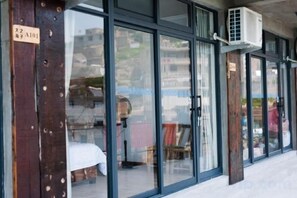 A hotel entrance with large glass doors, a wooden pillar with a sign, and an air conditioning unit mounted on the wall. - Dahai Zhizi Inn (Zhoushan)
