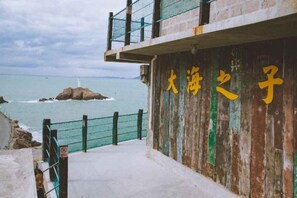 A coastal building with a wooden facade and a balcony overlooking the sea. - Dahai Zhizi Inn (Zhoushan)