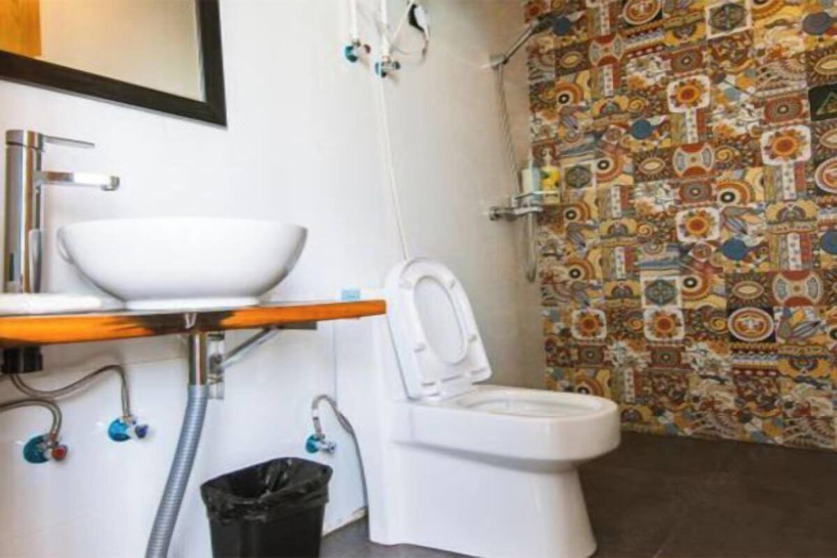 Et badeværelse med en hvid vask, toilet og en væg med et mønster i brusekabinen.