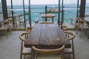 Una mesa de madera con sillas, con vistas a la costa y un faro a lo lejos.