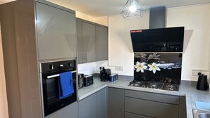 A modern kitchen with stainless steel appliances, a built-in oven, and a coffee machine.