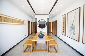 A long dining table with benches, a central bowl, and framed artwork on the walls.