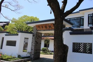 A building with a traditional architectural style, a sign with Chinese characters, and a tree in the foreground.