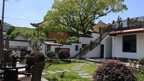 A courtyard with a dining area, a staircase, and a large tree. - Taohua Island Taoyuanli Homestay (Zhoushan)