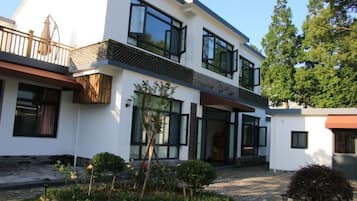Una casa moderna de dos pisos con amplios ventanales, un balcón y un jardín bien cuidado.