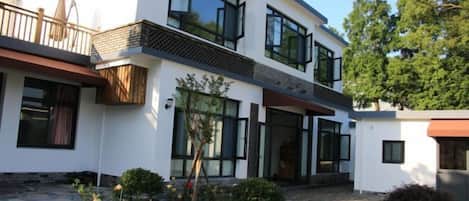 A modern two-story house with large windows, a balcony, and a well-maintained garden.