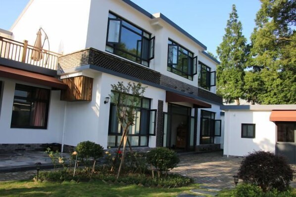A modern two-story house with large windows, a balcony, and a well-maintained garden. - Taohua Island Taoyuanli Homestay (Zhoushan)