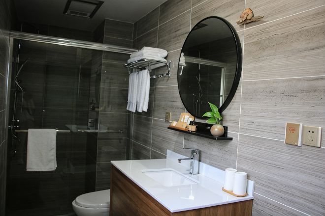 Un baño con cabina de ducha de vidrio, un lavabo blanco, un espejo y un perchero para toallas.