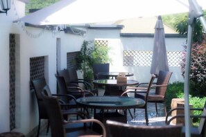 An outdoor patio with round tables and chairs, a potted plant, and a white umbrella. - Taohua Island Taoyuanli Homestay (Zhoushan)