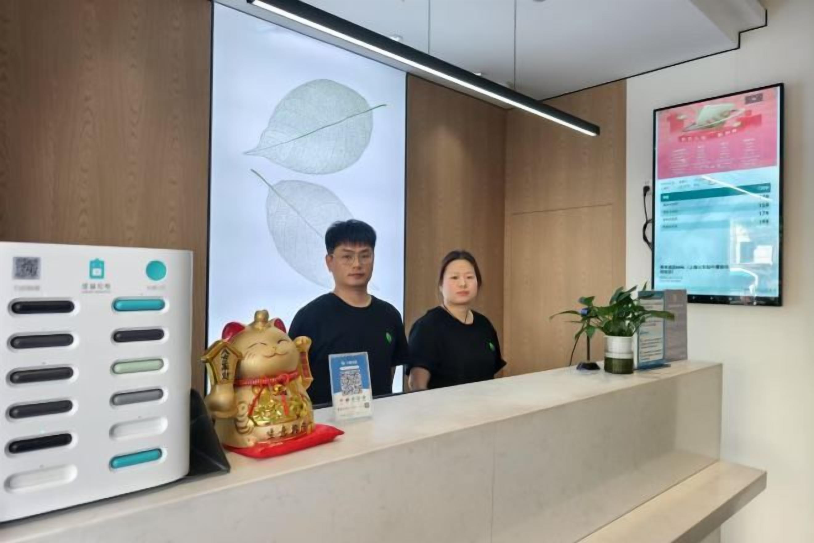 A reception desk with a QR code, a digital screen displaying information, and a decorative golden figure.