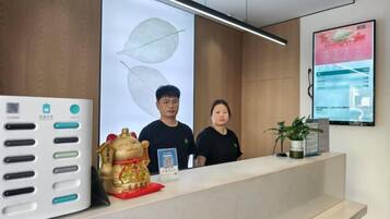 A reception desk with a QR code, a digital screen displaying information, and a decorative golden figure.