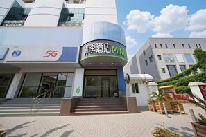 Ingresso di un hotel con un cartello 5G, la scritta MINI e una scalinata che conduce all'entrata.