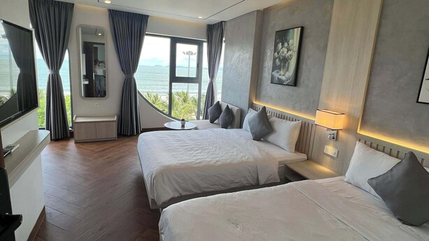 Habitación de hotel con dos camas, un ventanal con vistas, una mesita y un espejo.