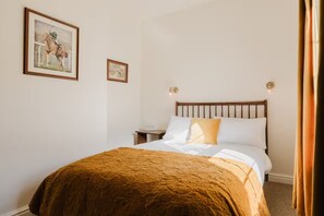 Comfortable bed with a wooden headboard, wall-mounted lights, and a framed picture on the wall.