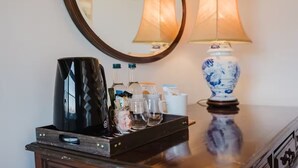 Een minibar met een koffiezetapparaat, flessen, glazen en een dienblad.