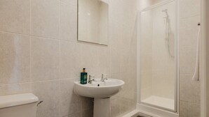 Een badkamer met een witte wastafel, een spiegel en een douchecabine.