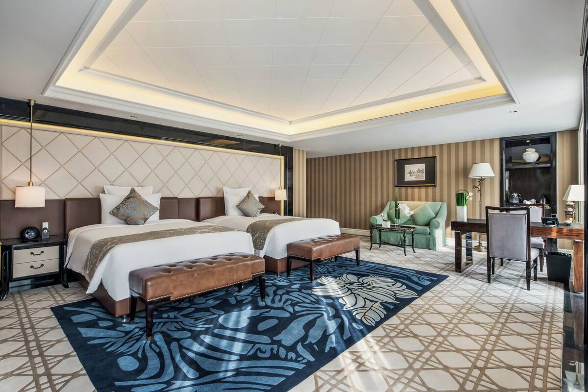 Quarto de hotel com uma cama grande, uma escrivaninha, uma cadeira e um sofá.